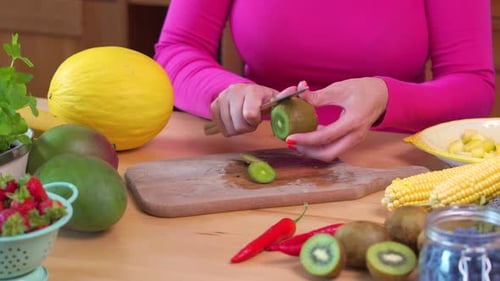 Woman in a Pink Blouse Chopping Juicy Green Kiwi