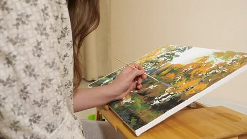 Woman Painting Landscape with Brush at Home