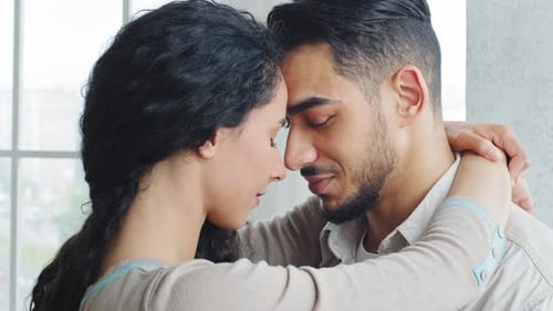 Loving Couple Embracing Affectionately Near a Window