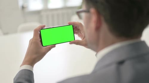 Man Looking at Smartphone with Green Chroma Screen