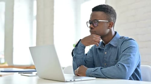 Focused Man Typing on Laptop in Bright Office