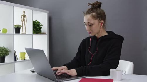 Attractive Female Freelancer with Headphones Works at Laptop, Talking on Webcam