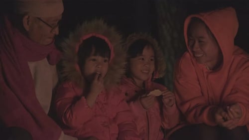 Family warms near campfire in forest and having a conversation. Night camping near bonfire.