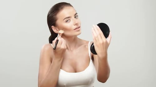 Woman Applying Makeup With Brush in Mirror