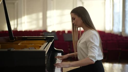 Woman Playing Piano in Concert Hall