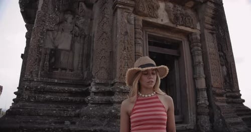 Woman Exploring Ancient Temple Ruins on Cloudy Day