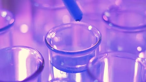 Gros plan d'une pipette avec un tube à essai en verre d'Intro de gouttes d'eau bleues liquides en laboratoire