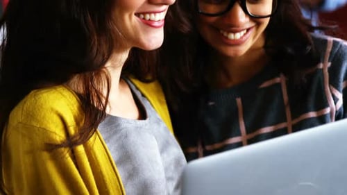 Smiling Women Collaborating Using a Laptop in Office