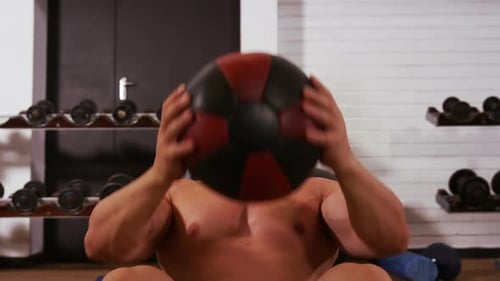 Man Performing Sit-ups With Medicine Ball in Gym