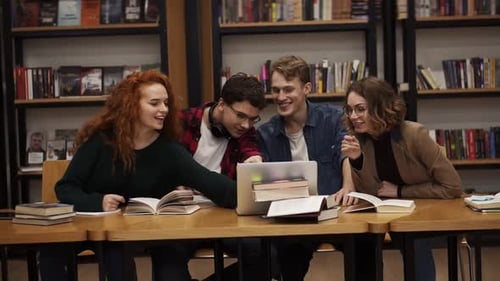Gruppe junger Studenten im Gespräch mit Laptop, erklärt Kursarbeit, gemeinsames Lernen in der Bibliothek