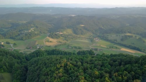 Green Slovenian countryside small hills covered with forest and meadows and lots of farms. Aerial 4k