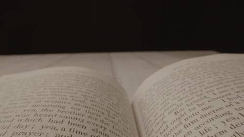 A camera shot floating across an open book with a black background and the book is later closed
