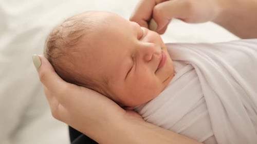 Sleeping Newborn Held Gently in Loving Hands