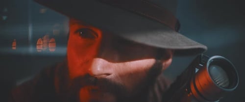 Close up of man looking into camera holding vintage camera