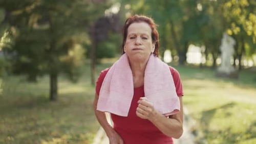 Femme mature fatiguée qui court dans le parc
