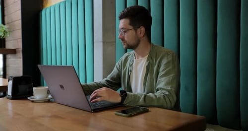 Man Working on Laptop in Cafe