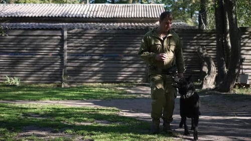 Man Training a Black German Shepherd Dog Outdoors