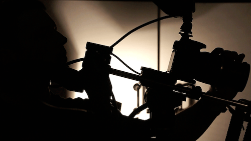 Man Adjusts Camera Equipment in Dark Studio