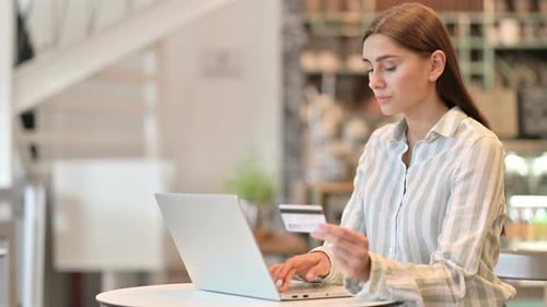 Young Latin Woman Using Smartphone and Laptop in Cafe
