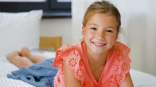 Happy Blond Girl Lying on Bed and Laughing