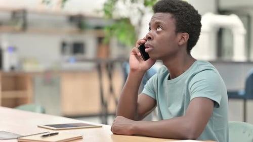 Young Adult Talking on Phone at Table