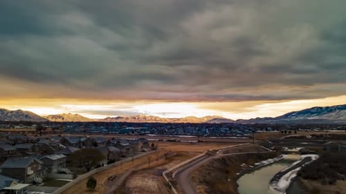 Gloomy cloudscape above the sunshine with an urban area below and the snow mountains in the distance