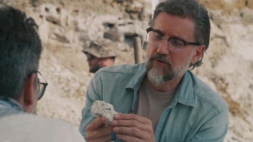 Mature Archaeologist Discussing Fossil with Colleague