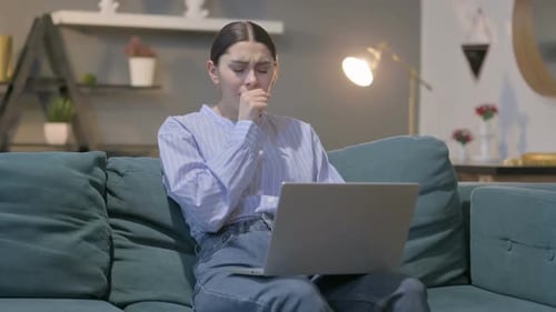Woman Coughing While Working on Laptop at Home