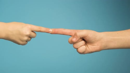 Two human hands touching each other with point fingers isolated on blue background.
