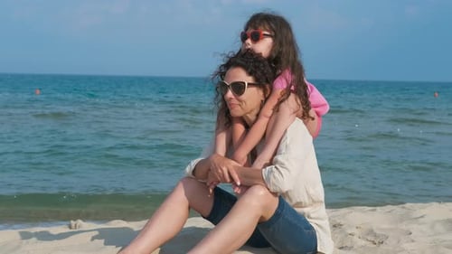 Mother and Daughter Relaxing on Sandy Beach