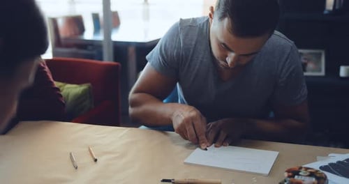 Man Carving Intricate Linocut Design with Sharp Knife