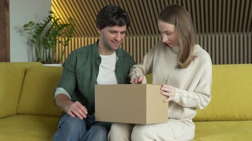 Couple Excitedly Opening a Box Together Indoors
