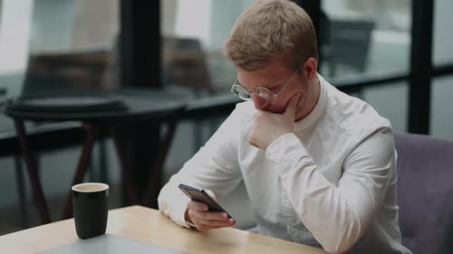 Adult Businessman Texting on Smartphone While Sitting By Laptop