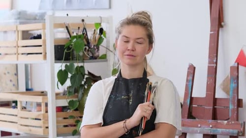 Female Artist Holding Brushes in Her Studio