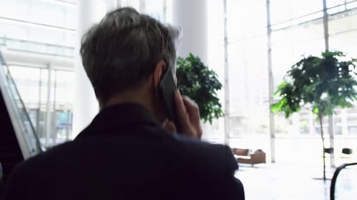 Businesswoman talking on mobile phone in the lobby at office 4k
