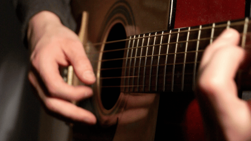 Person Playing Acoustic Guitar Close Up