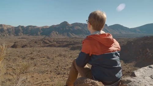 Boy Taking Pictures in a Mountainous Desert Landscape