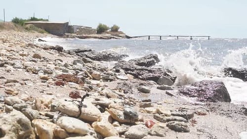 Close-up of a Rocky Seashore with Small Waves on a Sunny Summer Day