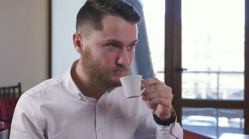 Young Attractive Man Sitting in Cafe and Drinking Coffee Slow Motion