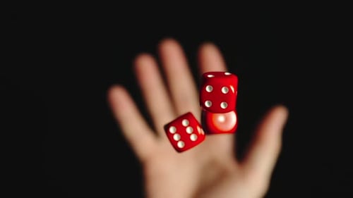 Hand Tossing Red Dice on Black Background