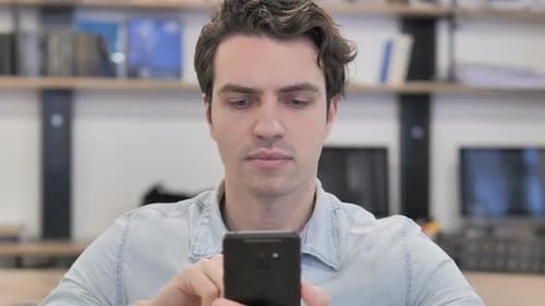Porträt eines kreativen Mannes mit Smartphone im Büro