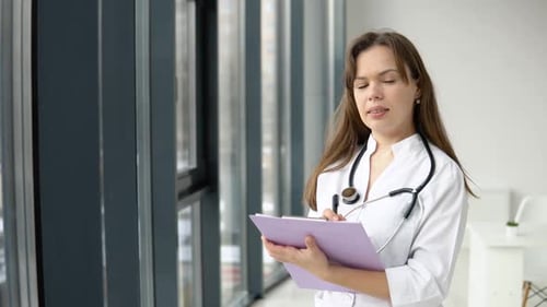 Young Caucasian Woman Doctor Wearing White Medical Coat and Stethoscope with Documents in Her Hands