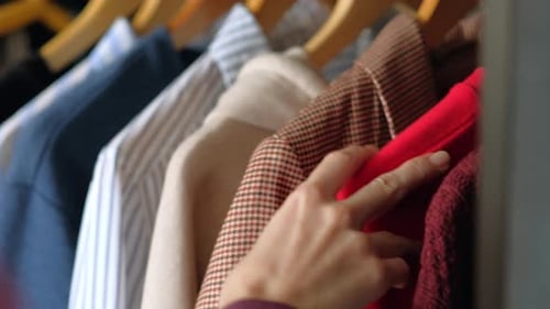 Hand Selecting Clothing from a Closet Rack