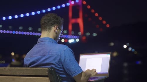 Man using laptop works at night by the sea.