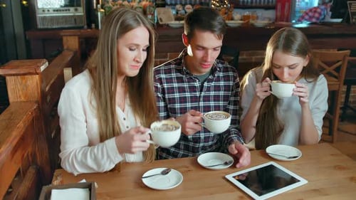 Group of Friends Drinking Coffee and Talking In Cafe