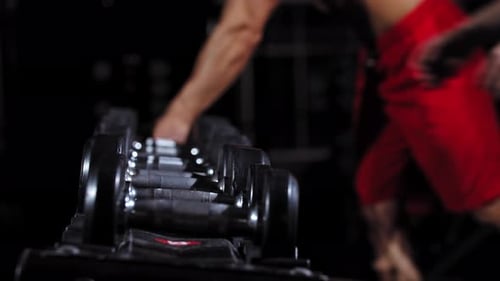 People Taking Dumbbells From the Stand in the Gym