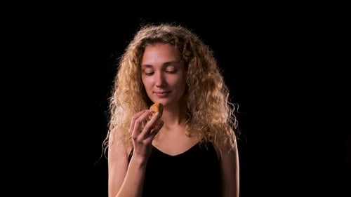 Woman Eats Pastry Against a Black Background