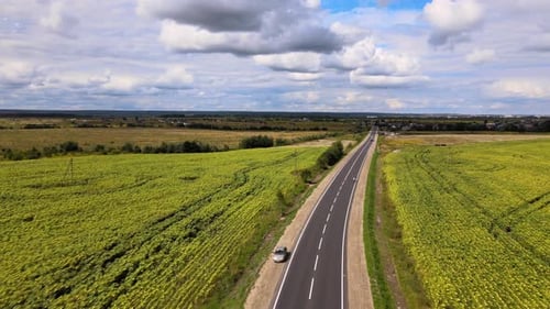 Aerial View of Intercity Road Between Green Agricultural Fields with Fast Driving Cars
