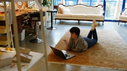 Woman Using Phone and Laptop Lying on Rug