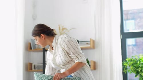 Woman Arranging Cushions at Home